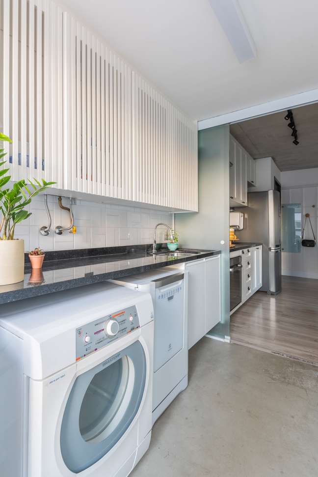 The gas stove in this laundry room brings with it a lot of features.  Through well thought-out slatted woodwork, Júlia managed to hide the device by creating a cabinet that contains niches for storing items from the environment.