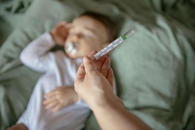 Lying baby and adult hand thermometer