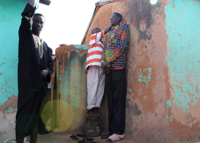 A neighbor stood on a stool to mark the wall when he measured Awuche's height A neighbor stood on a stool to mark the wall when he measured Awuche's height