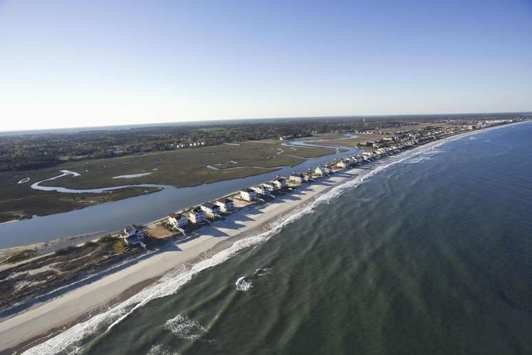 Ilha Pawleys, Estados Unidos. Areias brancas e casinhas à beira da praia, com um ambiente divertido e familiar, fizeram da Ilha Pawleys, no estado americano da Carolina do Sul, um dos destinos prediletos de férias para os habitantes da região durante o verão.  Com o rio Savannah de um lado e o Oceano Atlântico do outro, a ilha é tranqüila e compacta, o que a torna ideal para se locomover a pé ou de bicicleta. O desenvolvimento hoteleiro é limitado, e por isso, o melhor jeito de se hospedar é alugando uma casa frente ao mar