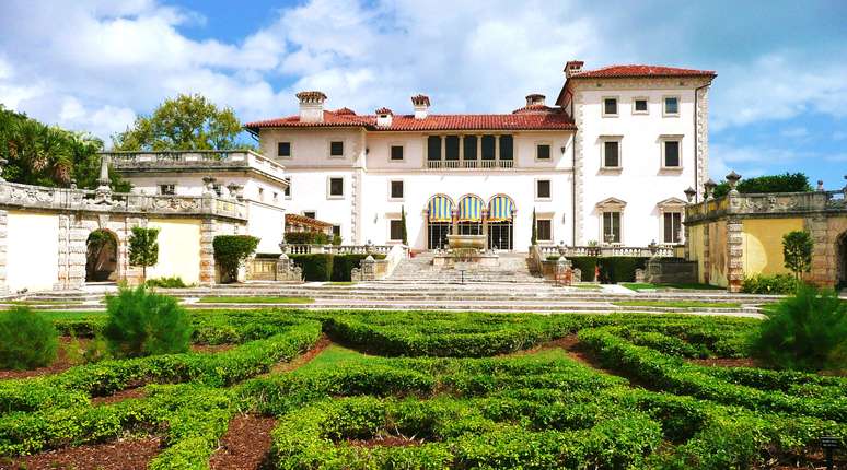 Vizcaya, Miami, Flórida - Rodeado por 10 hectares de jardins de inspiração europeia e um jardim de escultura privada, essa mansão tem vista para Miami Biscayne Bay. Concluída em 1916, a residência opulenta possui diversas salas feitas com arcos, colunas clássicas elaboradas e detalhes decorativos. A biblioteca esconde uma passagem secreta através da sua estante de livros e o salão de chá possui portas de vidro colorido, que permite que a luz cubra o chão de mármore liso