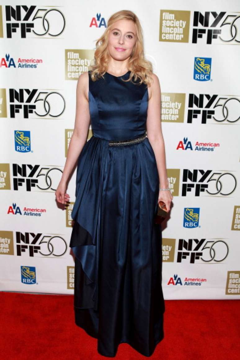 A atriz Greta Gerwig posa com vestido longo de cetim com pregas na saia, num visual equilibrado. Apenas o detalhe que cai do lado direito poderia ser dispensado, pois pesou e não embelezou o resultado