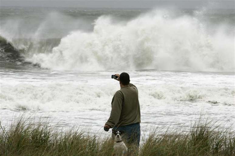 Homem passeando com cachorro tira foto das ondas provocadas pelo furacão Sandy em Ocean City, Nova Jersey. O Furacão Sandy tirou a eleição presidencial dos EUA do rumo neste domingo, antes mesmo de chegar ao país, forçando o republicano Mitt Romney a transferir a campanha para o interior e alimentando temores de que a enorme tempestade possa atrapalhar a votação antecipada na Costa Leste. 28/10/2012