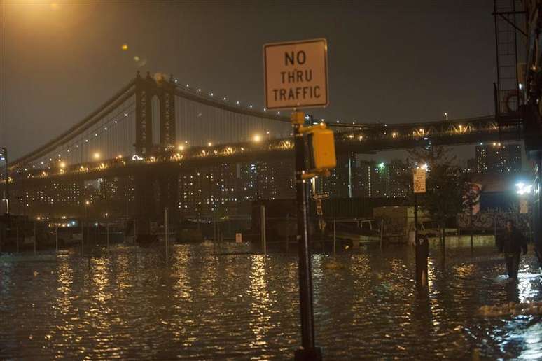 Homem tenta caminhar em rua alagada no bairro do Brooklyn durante tempestade Sandy em Nova York. 29/10/2012