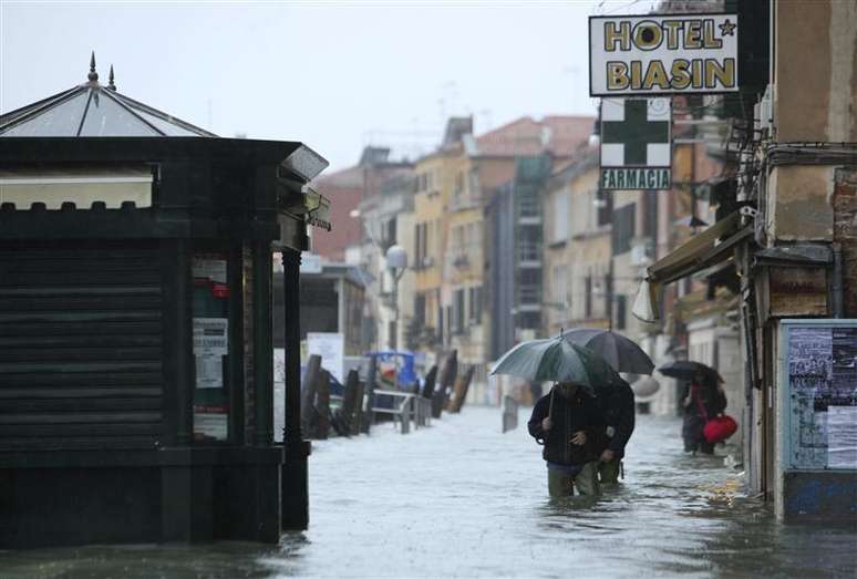 Pessoas caminham por rua alagada de Veneza. Cerca de três quartos da cidade ficaram alagados nesta segunda-feira, e os turistas aproveitaram para nadar na Praça de São Marco, depois de fortes chuvas que atingiram a região norte e central da Itália, forçando 200 pessoas a deixarem suas casas na Toscana.