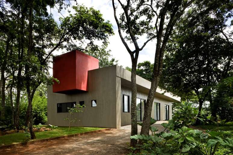 Do lado de fora da casa, a caixa dágua vermelha ganha grande destaque e reforça o formato geométrico ao projeto