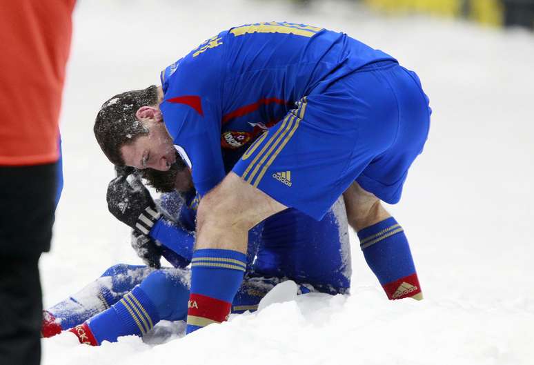 Mamayev (sentado) e Dzagoev comemoram no meio da neve, fora do campo, o segundo gol do CSKA