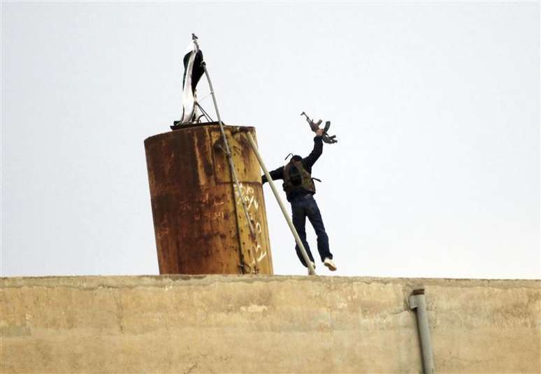 Membro do Exército Sírio Livre pula depois de retirar bandeira oficial &nbsp;e erguer bandeira da oposição, na cidade de Ras al-Ain