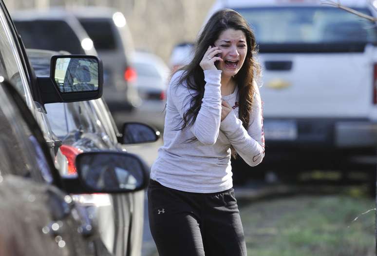 Mulher chora enquanto espera por notícias da irmã, uma professora na escola Sandy Hook