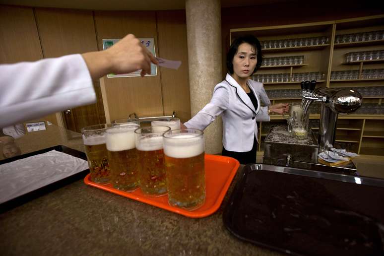 Garçonete leva canecos de cerveja para clientes do restaurante Mansugyo, em Pyongyang, na Coreia do Norte. Segundo a agência de notícias <i>AP</i>, este tradicional estabelecimento foi reformado por ordem do líder Kim Jong-um - há um ano no comando do país - após passar décadas mal cuidado<br />