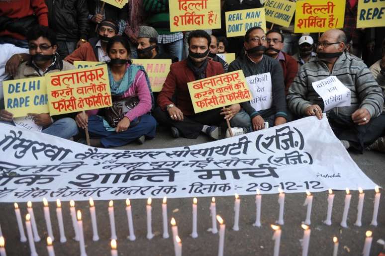 Amordaçados em frente a velas acesas, manifestantes prestam homenagem à vítima de estupro na Índia