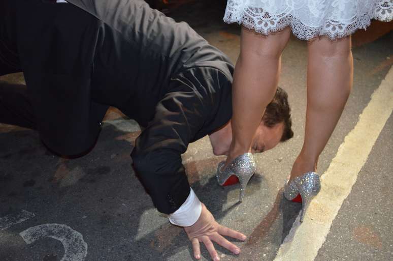 Diante de fotógrafos, Cachoeira repetiu o gesto feito na cerimônia fechada e beijou os pés da noiva