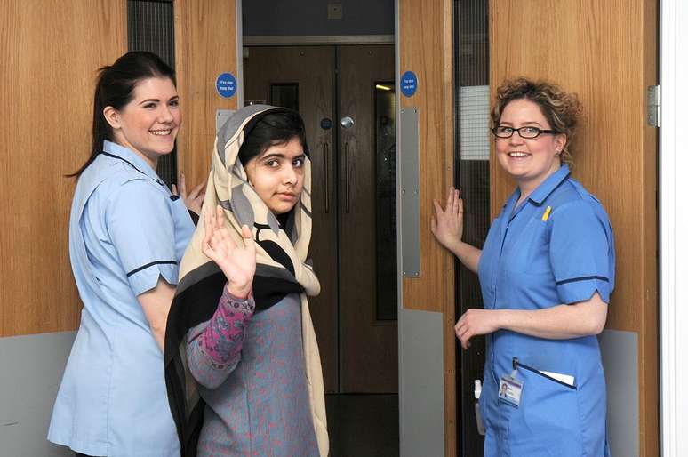 A estudante paquistanesa Malala Yousufzai (centro) acena ao lado de enfermeiras após receber alta do hospital Queen Elizabeth, em Birmingham