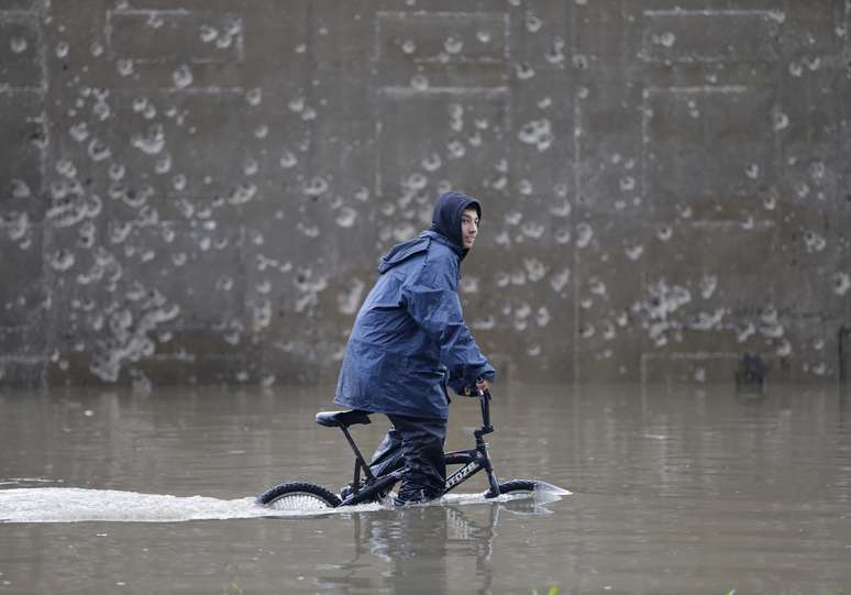 Menino anda de bicicleta em rua alagada de Beirute, no Líbano. O país foi atingido nos últimos dias por uma tempestade de neve que provocou o fechamento de estradas nas regiões montanhosas e foi sucedida por fortes chuvas na capital e em áreas costeiras no domingo