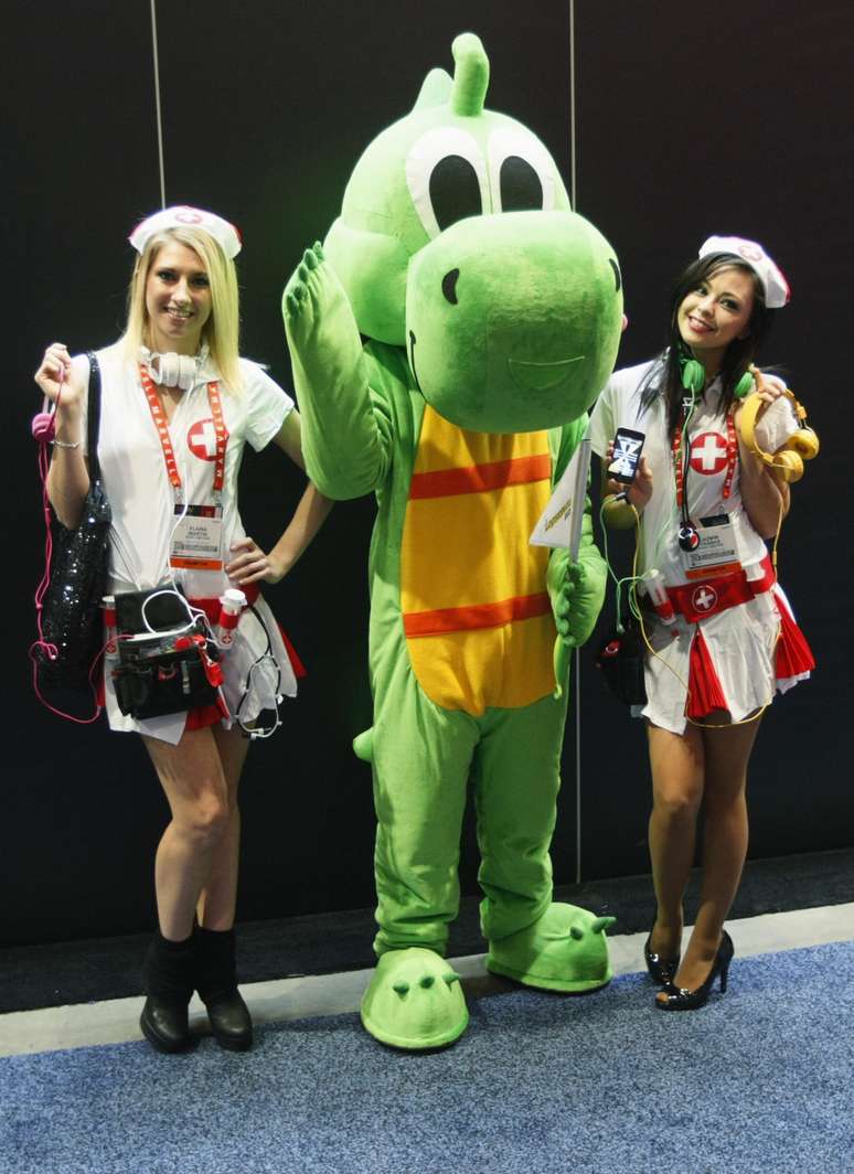 <strong>8 de janeiro de 2013</strong> - Mulheres vestidas como enfermeiras promovem um produto ao lado de participante vestido como dinossauro no primeiro dia da CES