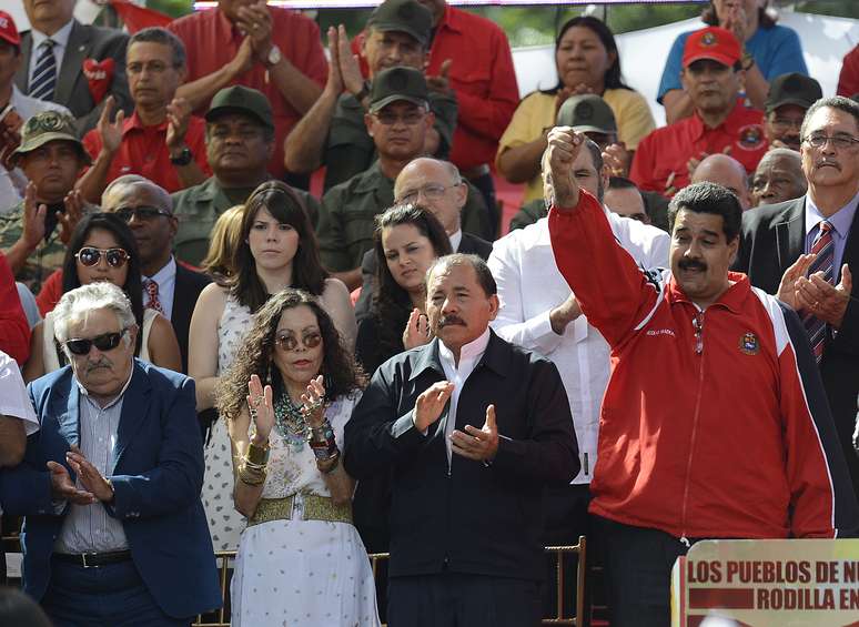 Nicolás Maduro inicia discurso em apoio a Chávez em Caracas; à esquerda, José Mujica, presidente uruguaio
