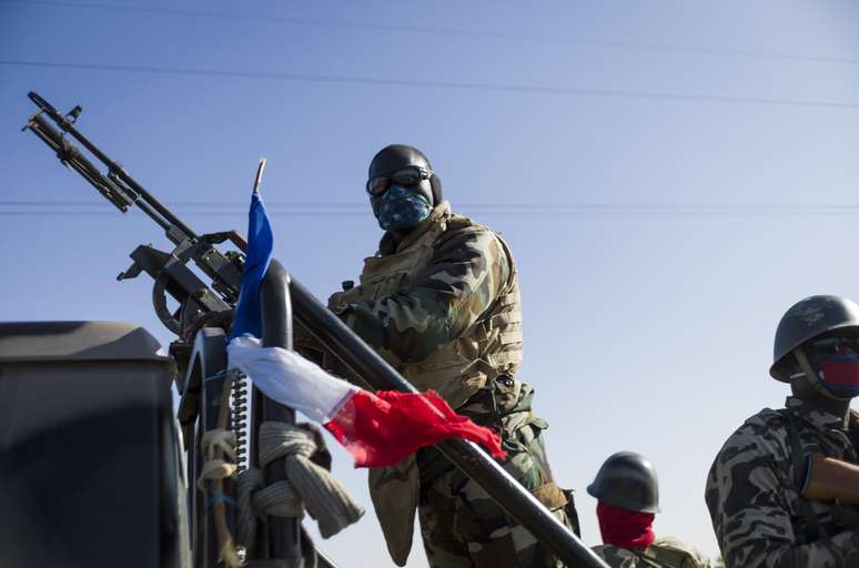 Soldado do Exército do Mali segura metralhadora enrolada na bandeira francesa durante viagem a Niono