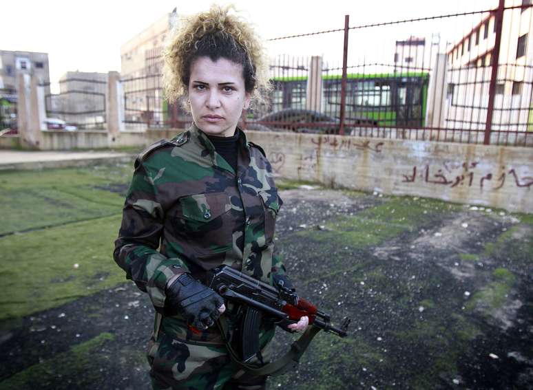 Mulheres segura rifle após terminar treinamento junto às forças sírias. Cerca de 450 trabalhadores foram recrutadas para servir de forma voluntária, formando a primeira unidade feminina do Exército paramilitar do presidente Bashr al-Assad em meio à guerra civil síria