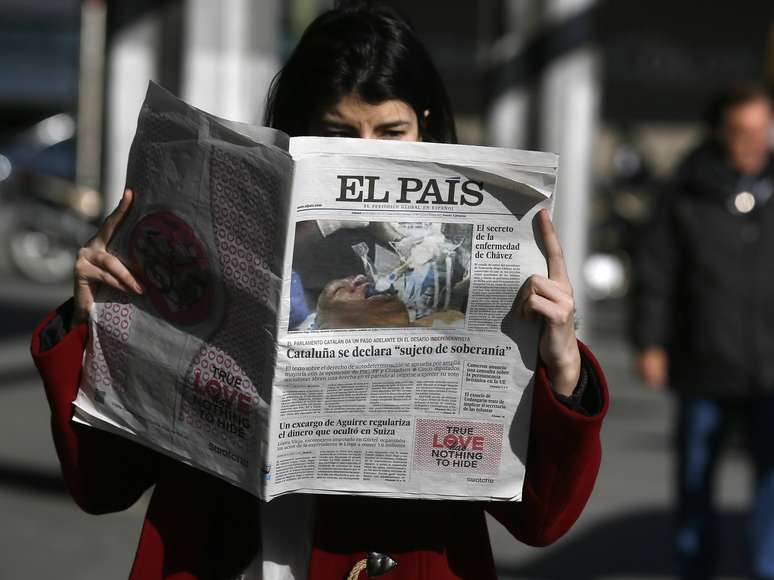 Mulher lê a versão do 'El País' impressa com a foto falsa de Hugo Chávez no centro de Madri, na Espanha