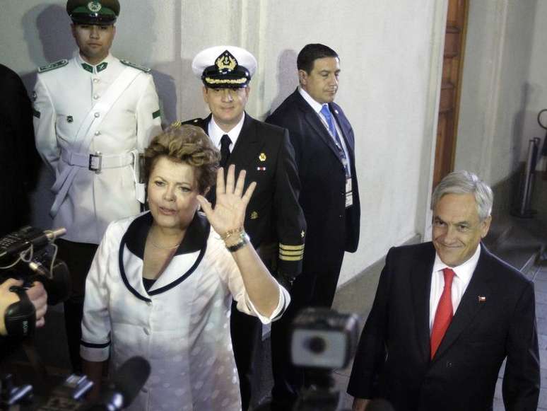 Dilma Rousseff acena para jornalistas ao lado do presidente do Chile Sebastián Piñera após chegar ao palácio La Moneda