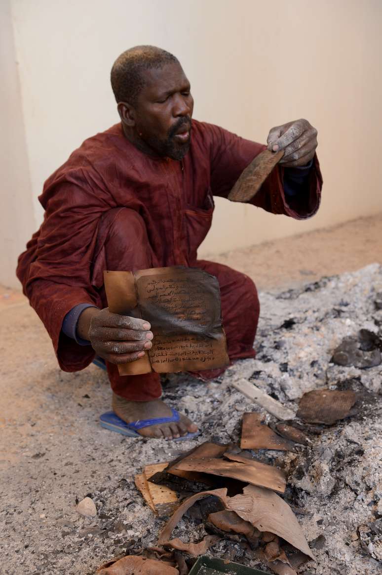 Homem observa manuscrito parcialmente queimado em Timbuktu após expulsão dos terroristas islâmicos