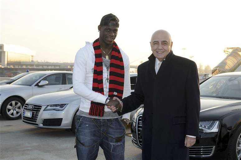 Jogador Mario Balotelli (E) da Itália cumprimenta vice-presidente do AC Milan, Adriano Galliani, na chegada ao aeroporto de Milão. 30/01/2013