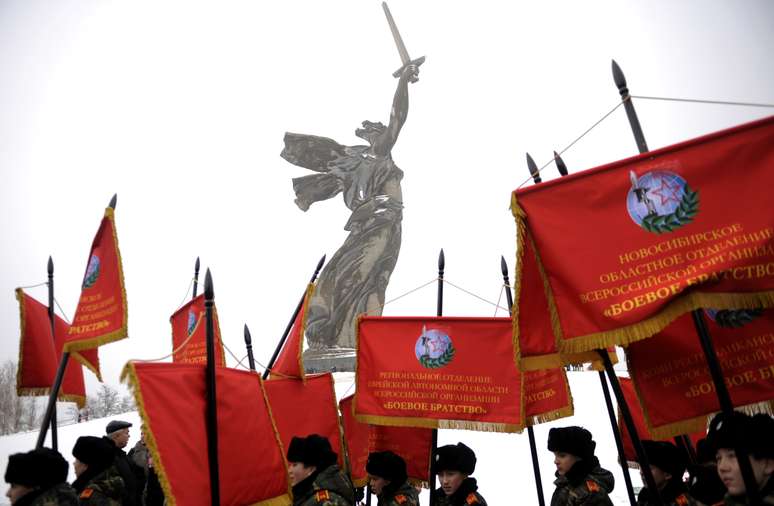 Estudantes tremulam flâmulas vermelhas na base do monumento épico da Mãe-Pátria erigido em nome da força da Rússia e dos soviéticos