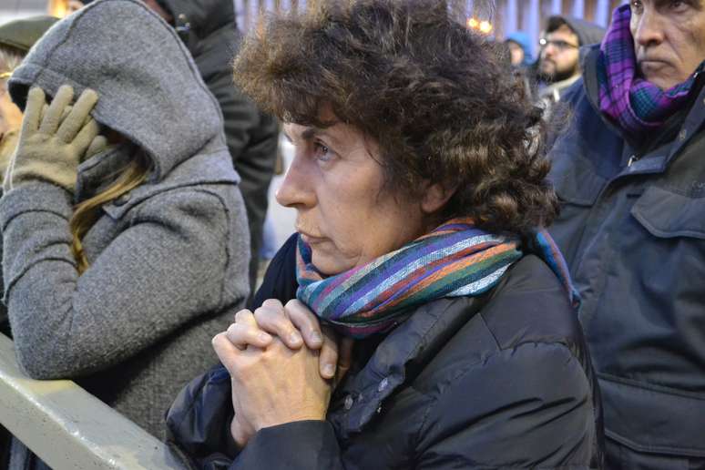Mulher reza diante de um dos telões durante o início da noite fria em São Pedro