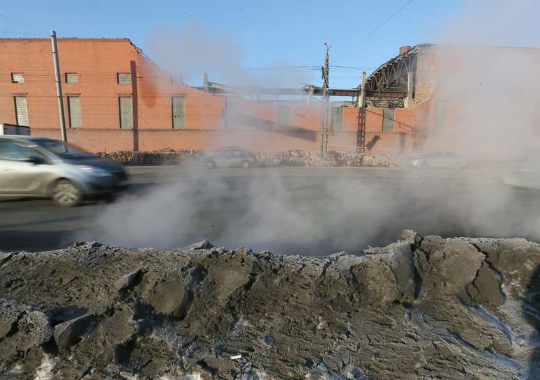 <p>Carros passam ao lado dos destroços do muro que desabou após a passagem do meteorito na Rússia</p>