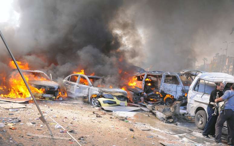Carros queimam após serem atingidos pela explosão nas proximidades da sede do partido governista Baath, em Damasco