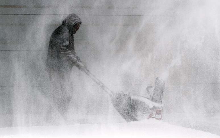 Tom McReynolds tenta remover a neve da entrada da casa de um vizinho em Wichita, Kansas