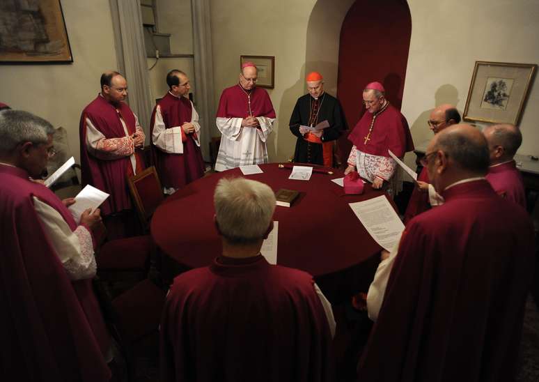 Tarcisio Bertone assume como cardeal camerlengo ao lado de demais cardeais iniciando o período de Sé Vacante no Vaticano