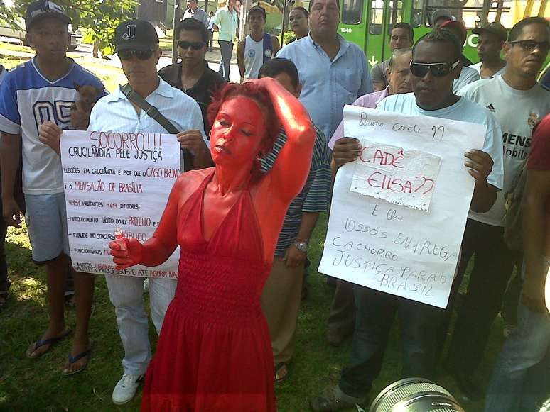 Mulher com o corpo todo pintado de vermelho protesta em frente ao Fórum de Contagem