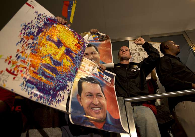 Apoiadores argentinos do venezuelano Hugo Chávez seguram imagens do líder na área externa da embaixada da Venezuela em Buenos Aires