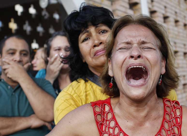 Apoiadores do presidente venezuelano choram após vice-presidente do país anunciar a morte do líder