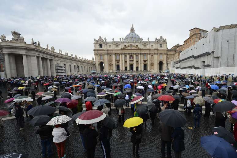 <p>Sob guarda-chuvas, para se proteger da precipitação intermitente no Vaticano, devotos aguardam fumaça</p>