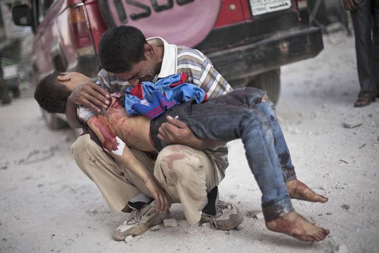 Pai chora segurando o corpo do filho, morto pelo Exército Livre da Síria, perto ao hospital Dar el-Shifa, em Aleppo