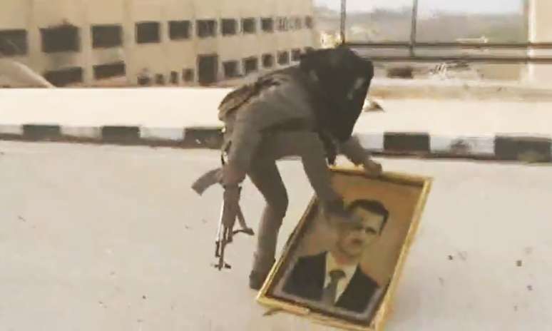 Rebelde sírio pisa sobre retrato do presidente Bashar al-Assad em imagem divulgada através das redes da oposição