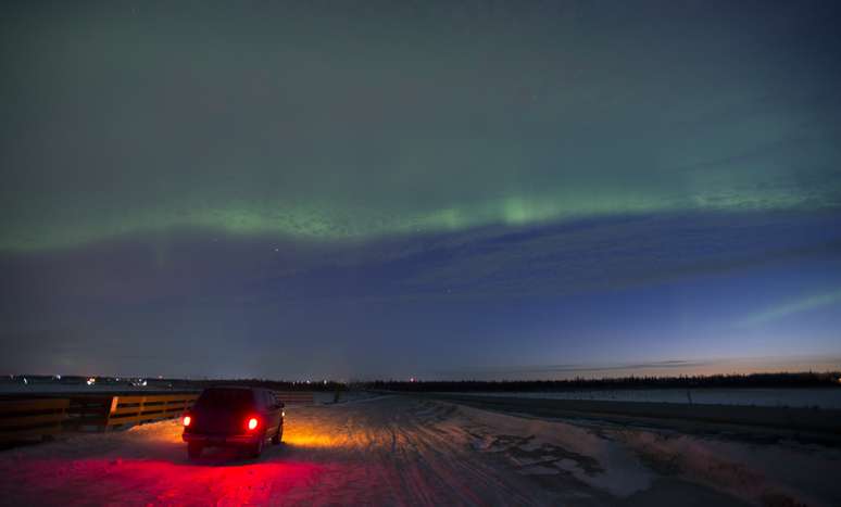 Em Kenai, no Alaska, Estados Unidos, um motorista para na estrada para adimirar o fenômeno neste domingo