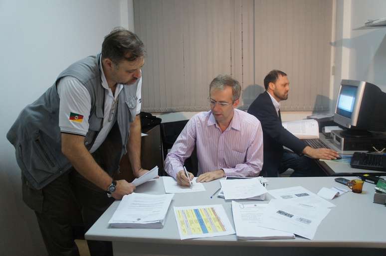 <p>Os delegados Marcelo Arigony (ao fundo) e Sandro Meinerz (centro) se reuniram com a equipe para analisar o relatório final do inquérito</p>