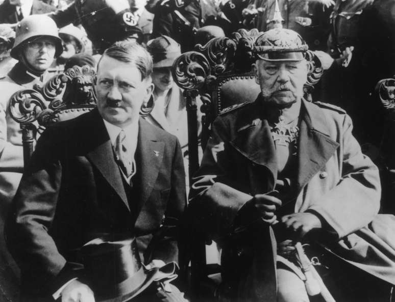 <p>O chanceler Adolf Hilter e o presidente Paul von Hindenbyrg, juntos em evento de 1933 de comemoração de uma vitória sobre os russos em 1914</p>