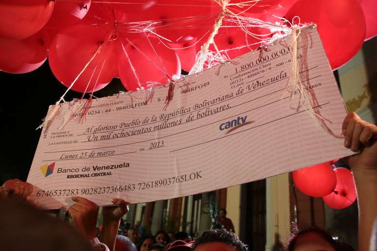 Imagem mostra o cheque sendo erguido por balões vermelhos