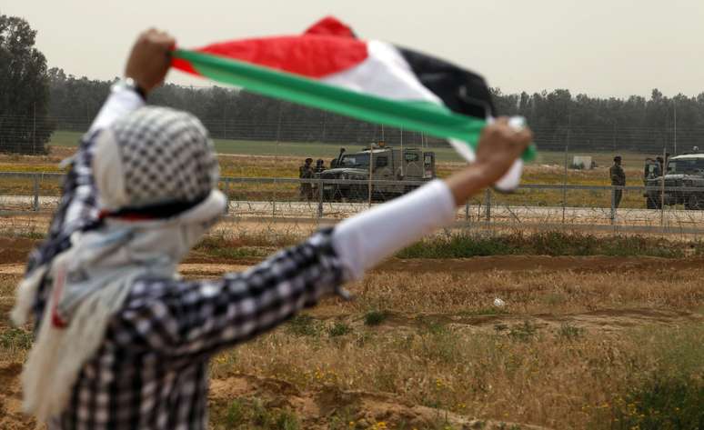 Manifestante exibe bandeira palestina durante protesto no sul da Faixa de Gaza