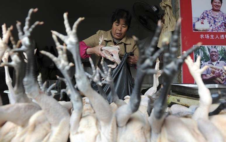 Vendedora empacota galinhas em mercado de aves em Hefei. A China encontrou dois novos casos de uma nova cepa da gripe aviária, e uma das vítimas morreu, na cidade de Hangzhou, informou a mídia estatal nesta quarta-feira, elevando para nove o número de casos registrados.