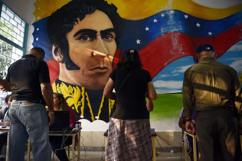 Com a imagem do libertador Simón Bolívar ao fundo, venezuelanos votam em Caracas