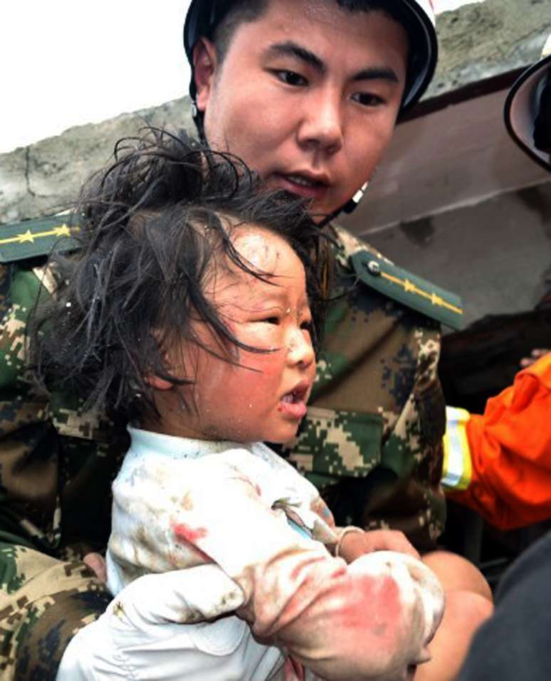 Equipe de resgate carrega criança para fora de dua casa após terremoto que atingiu a  a província central chinesa de Sichuan, neste sábado 