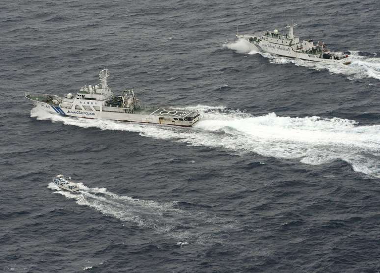 Navio da Guarda Costeira japonesa navega entre barco pesqueiro e embarcação de vigilância chinesa (no topo) nas proximidades das ilhas Senkaku