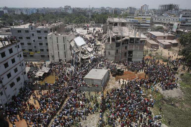 Multidão se aglomera ao redor do prédio que desabou em Bangladesh enquanto pessoas tentam resgatar sobreviventes presos nos destroços, em Savar. 24/04/2013. O prédio de oito andares que abrigava fábricas e um shopping center desabou nesta quarta-feira na periferia da capital de Bangladesh e deixou cerca de 100 pessoas mortas e centenas de feridos, disseram autoridades do governo.