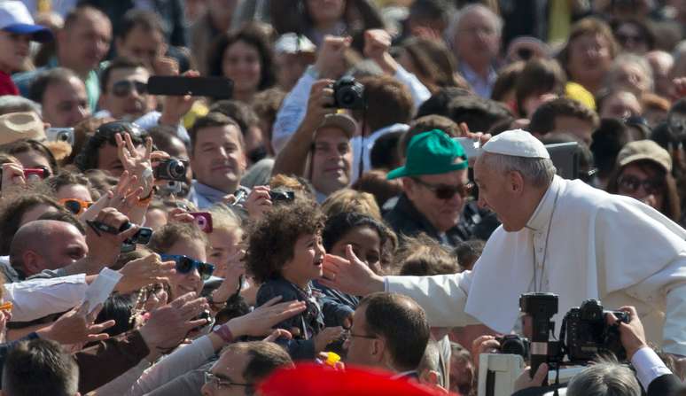 Papa interage com criança ao chegar para a audiência geral na Praça São Pedro 