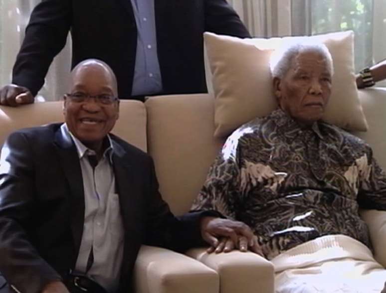 <p>Em torno dele, os líderes do ANC - partido no poder - posam sorridentes para a televisão</p>